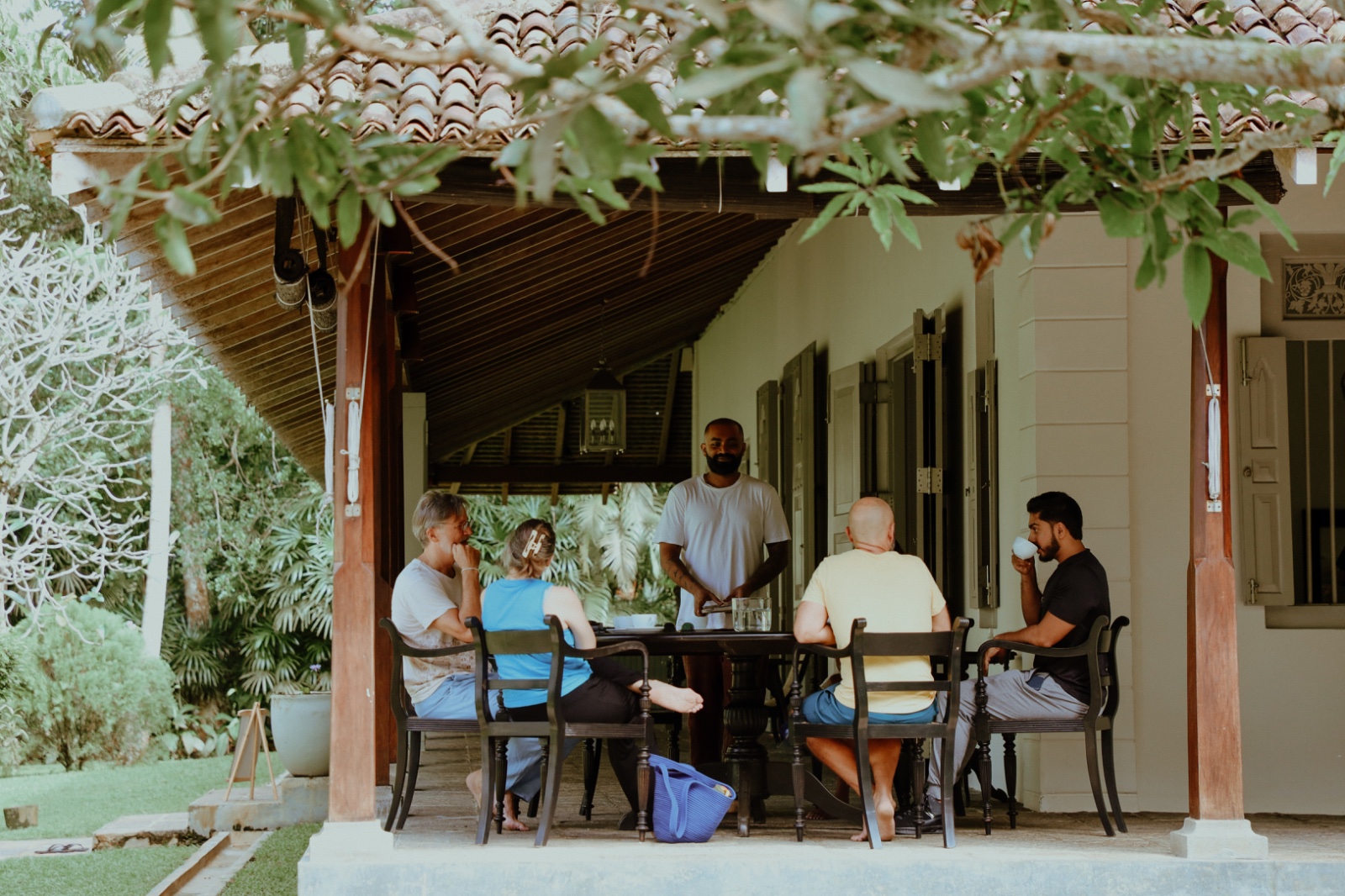 A small group sharing tea and conversation on a Sri Lankan veranda.